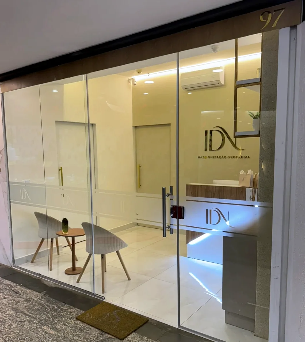 Fachada de vidro do instituto no corredor do Fashion Mall, com o número 97 em dourado acima da porta e a recepção iluminada ao fundo.